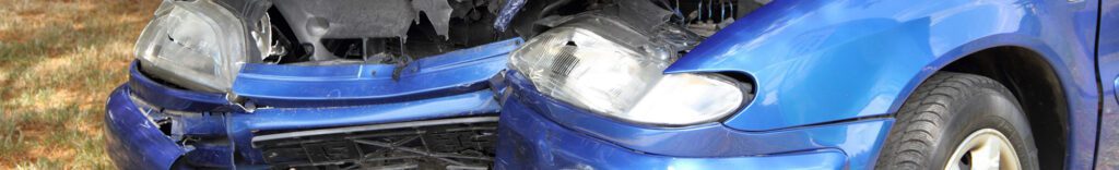 The front end of a blue car smashed in from an accident.